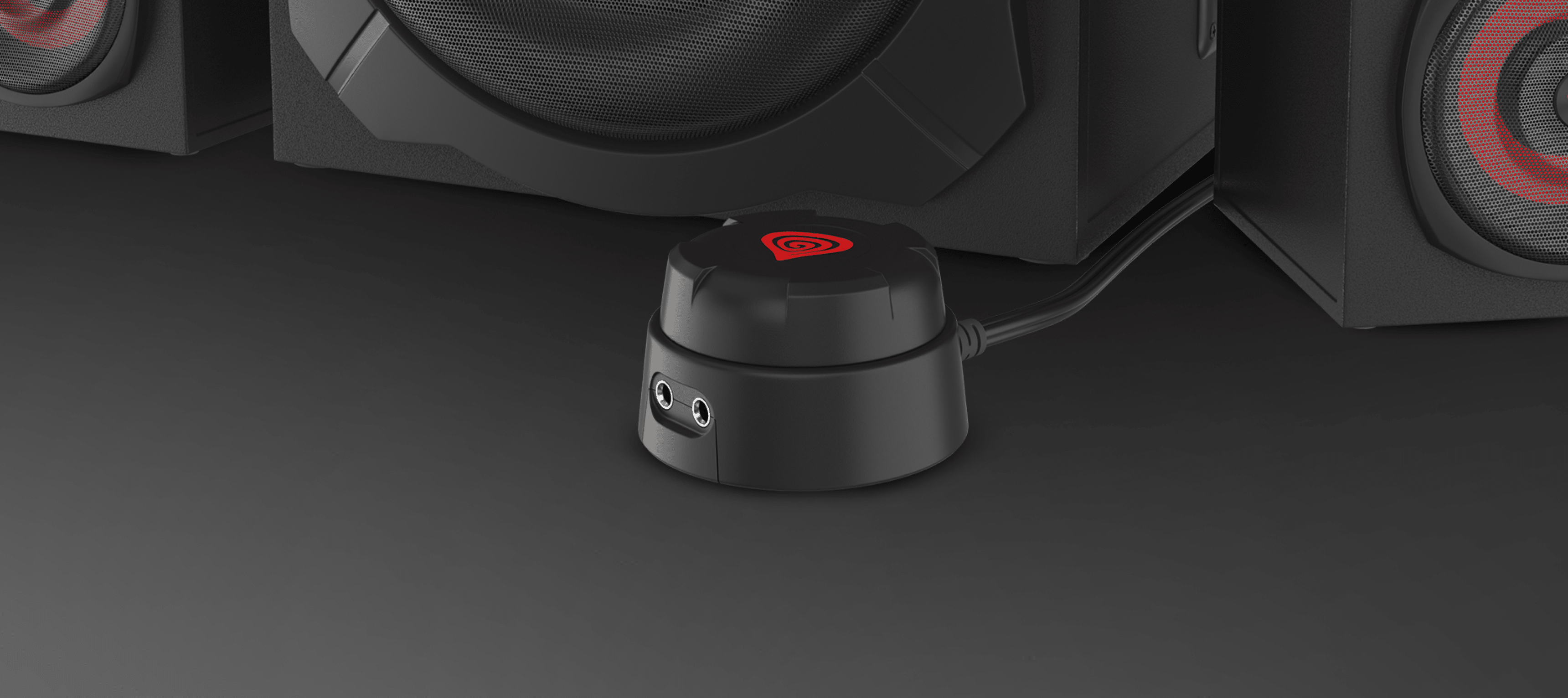 Czarny pilot przewodowy do głośników Genesis Helium 610BT, wyposażony w wejścia audio, umieszczony w pobliżu subwoofera.