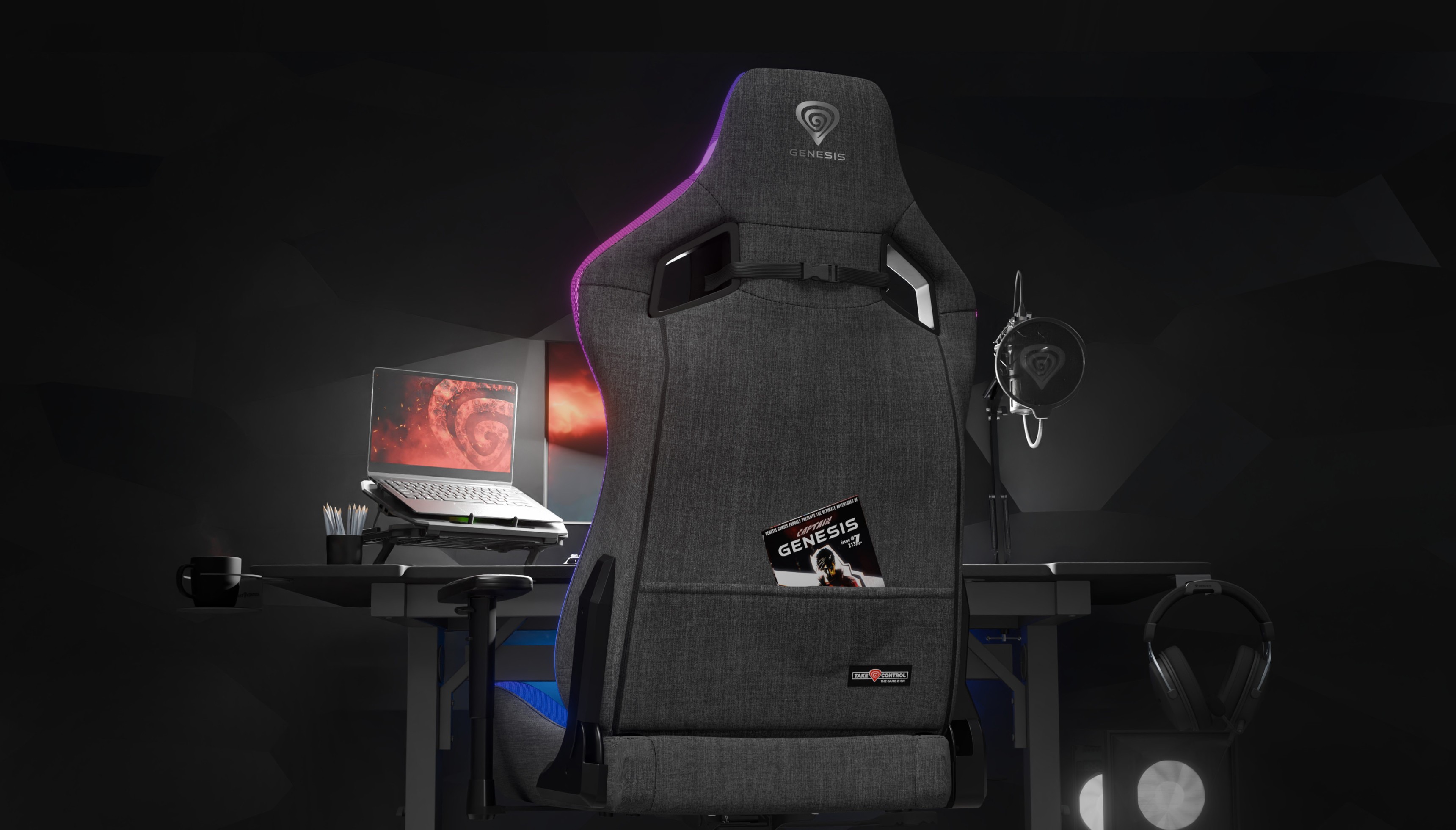 Szary fotel gamingowy Genesis Trit 660 RGB ustawiony przed biurkiem z laptopem i akcesoriami do gier. Widoczne akcenty świetlne RGB