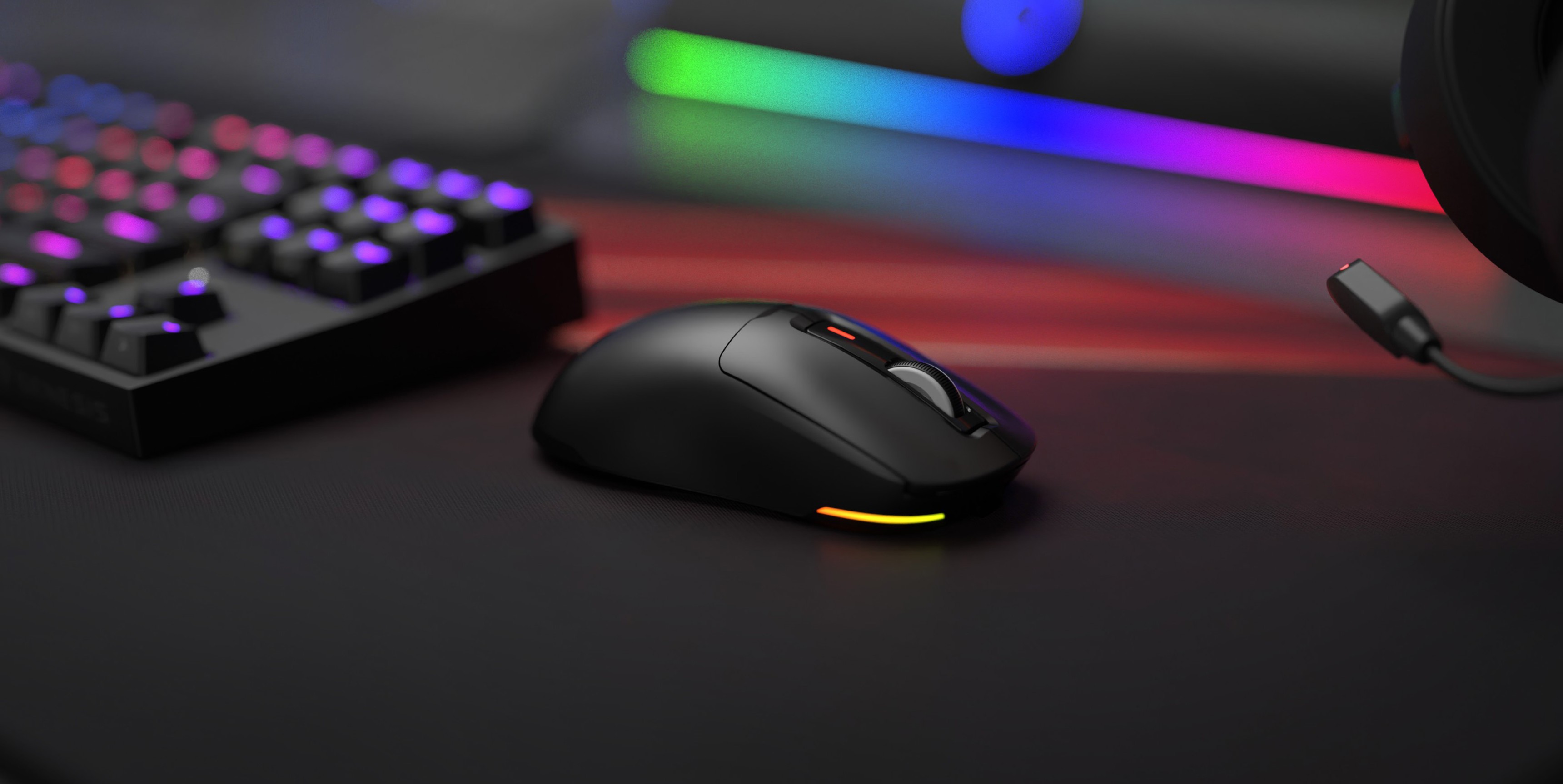 Czarna bezprzewodowa mysz do gier Genesis Zircon 660 z podświetleniem RGB, umieszczona na eleganckim biurku gamingowym obok klawiatury mechanicznej